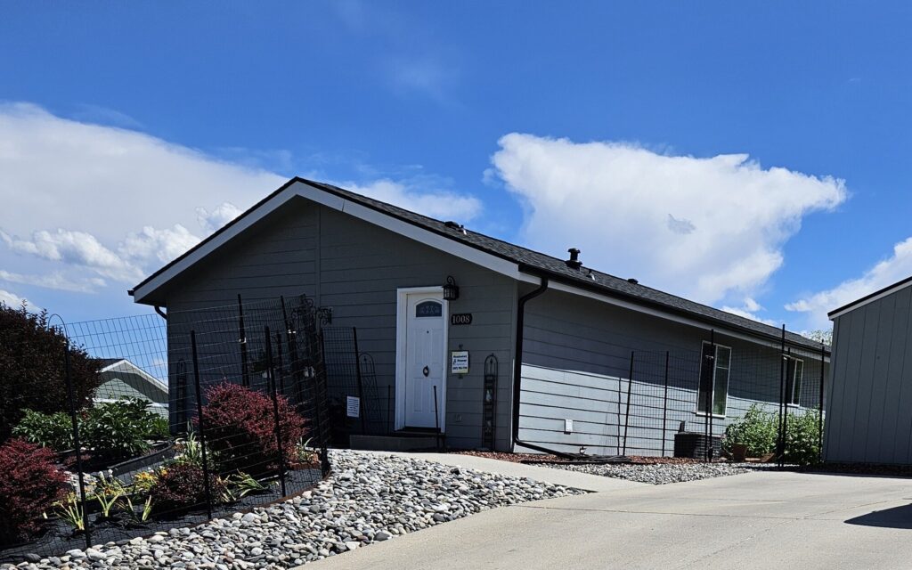 The gray single-story building at 1008 S. Main St with a white front door